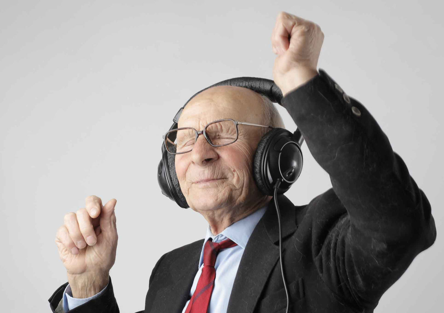 Elderly man with hands in the air listening to music on his headphones