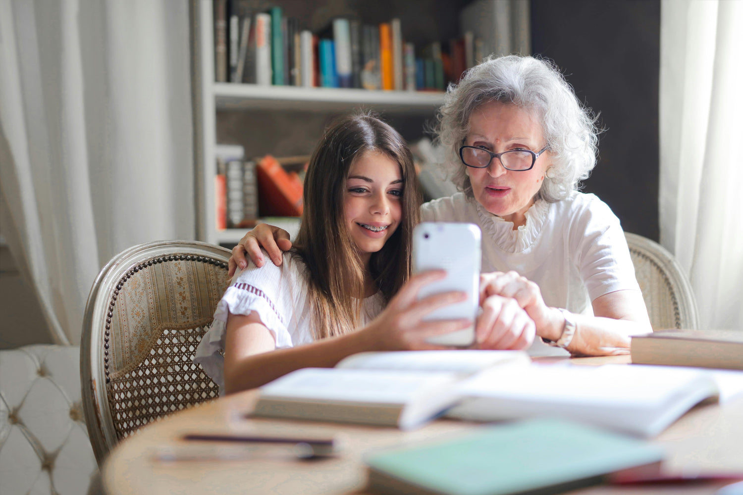 Elderly woman with grand daughter studying and looking at the phone together